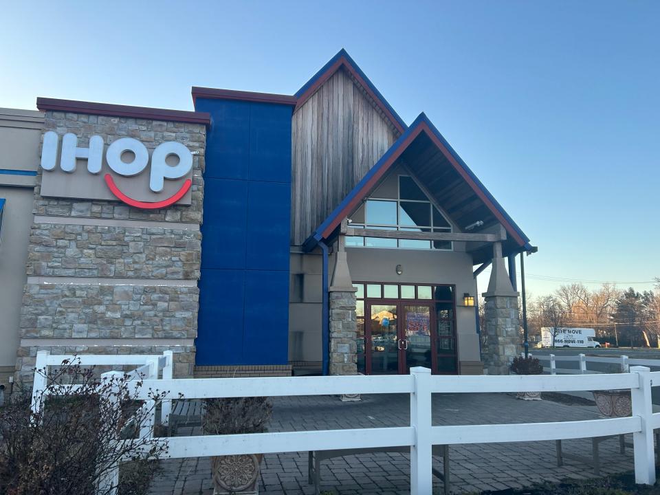 Exterior of an IHOP with logo, blue painted wall, and peaked roof. The entrance has brick pillars