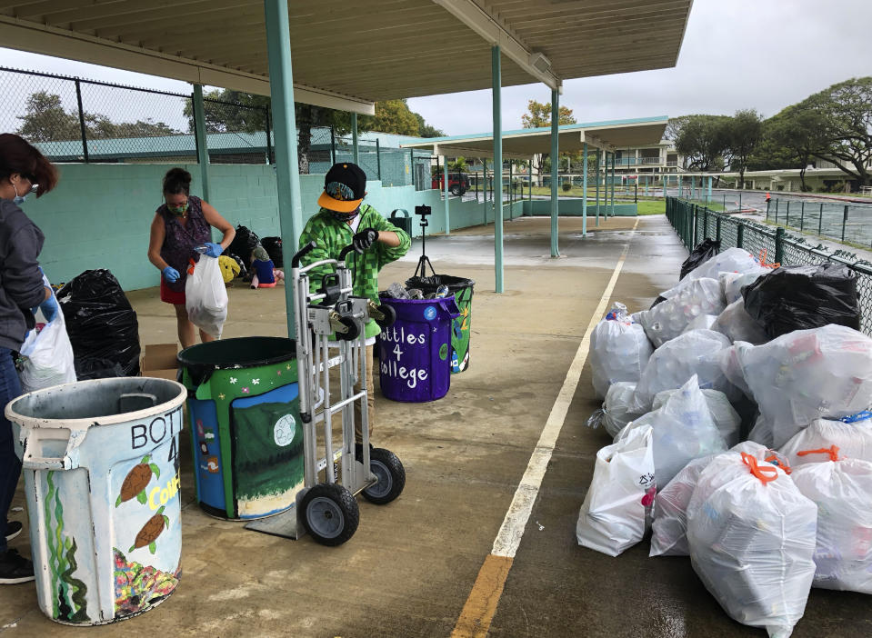 In this March 18, 2021, photo provided by Maria Price, Genshu Price, right, and other volunteers at S.W. King Intermediate School in Kāne'ohe, Hawaii, sort cans and bottles for Bottles4College, a recycling project he started that raises money for students' college tuition. (Bottles4College via AP)