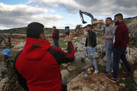 In this Thursday, Dec. 13, 2018 photo, Lebanese villagers smoke a water pipe and take souvenir pictures in front of Israeli excavators, in the southern border village of Mays al-Jabal, Lebanon. As Israeli excavators dig into the rocky ground, Lebanese across the frontier gather to watch what Israel calls the Northern Shield operation aimed at destroying attack tunnels built by Hezbollah. But Lebanese soldiers in new camouflaged posts, behind sandbags, or inside abandoned homes underscore the real anxiety that any misstep could lead to a conflagration between the two enemy states that no one seems to want. (AP Photo/Hussein Malla)