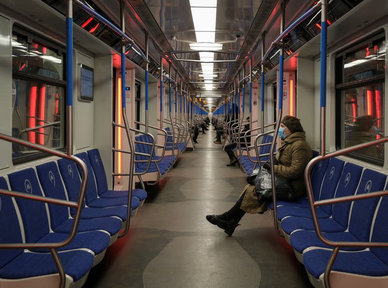 FILE PHOTO: A woman wearing a protective mask rides in a metro train in Moscow