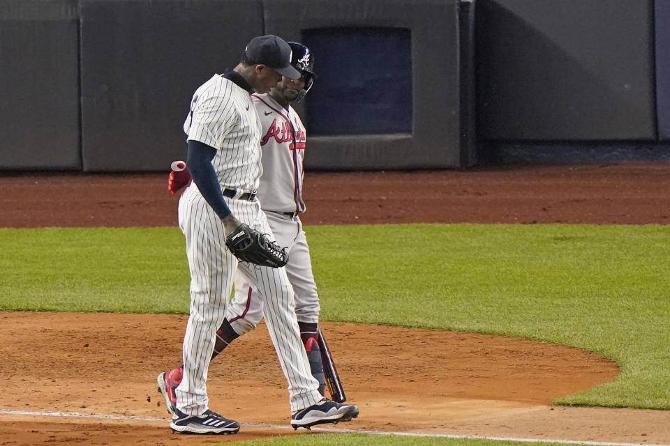 New York Yankees relief pitcher Aroldis Chapman, front, walks with Atlanta Braves' Guillermo Heredia after Heredia popped out in foul territory for the final out in the Yankees' 3-1 victory in a baseball game Tuesday, April 20, 2021, at Yankee Stadium in New York. Both players are from Cuba. (AP Photo/Kathy Willens)