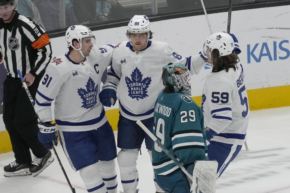 Toronto Maple Leafs right wing William Nylander, top middle, is congratulated by center John Tavares, left, and left wing Tyler Bertuzzi (59) after scoring a goal past San Jose Sharks goaltender Mackenzie Blackwood (29) during the third period of an NHL hockey game in San Jose, Calif., Saturday, Jan. 6, 2024. (AP Photo/Jeff Chiu)