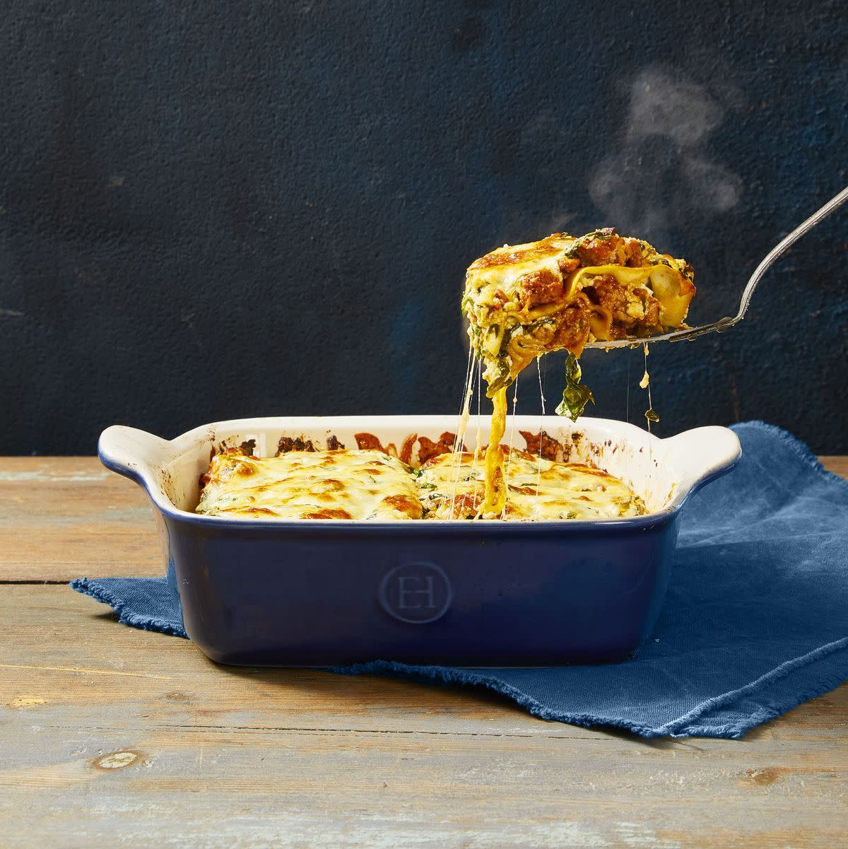 lasagna with meat sauce in a blue ceramic casserole dish