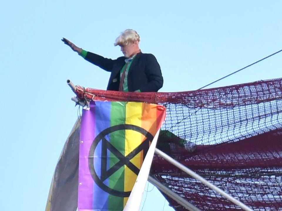 An Extinction Rebellion protester who scaled the scaffolding surrounding Big Ben unfurls a banner: Dominic Lipinski/PA