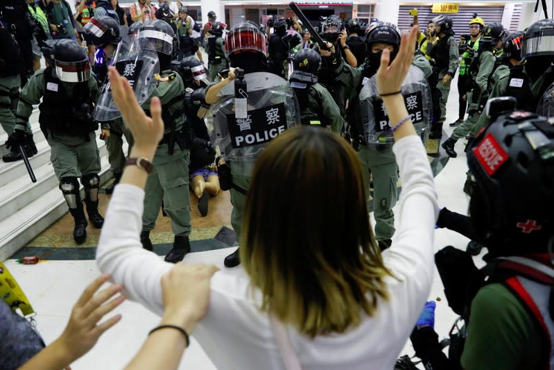 An anti-government protester raise her hands as riot police use pepper spray at shopping mall in Tai Po, Hong Kong