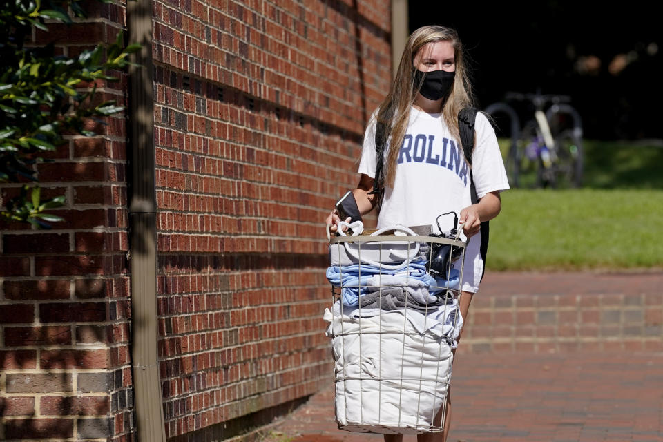 Freshman Sarah Anne Cook carries her blongings as she packs to leave campus following a cluster of COVID-19 cases at the University of North Carolina in Chapel Hill, N.C., Tuesday, Aug. 18, 2020. The university announced that it would cancel all in-person undergraduate learning starting on Wednesday while some students chose to pack and leave. (AP Photo/Gerry Broome)