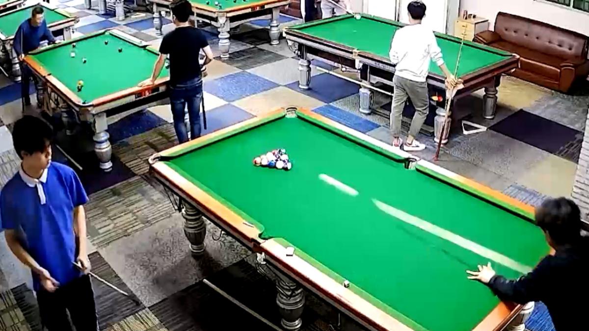 Pool player pots two balls on another table in unbelievable shot