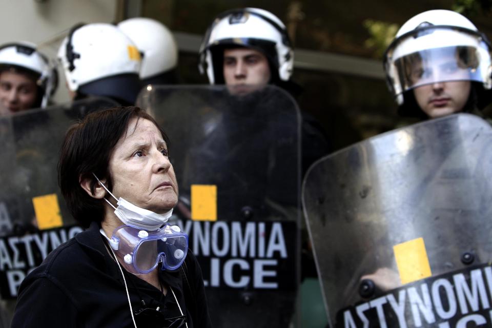 A protester stands in front of riot police securing the private office of Greek Public Administration Reform Minister Kyriakos Mitsotakis in central Athens, on Thursday, March 20, 2014. Scores of striking schoolteachers and other civil servants occupied Mitsotakis' office Thursday to protest planned public sector layoffs, under cost-cutting reforms demanded by the debt-mired country's bailout creditors. (AP Photo/Thannasis Stavrakis)