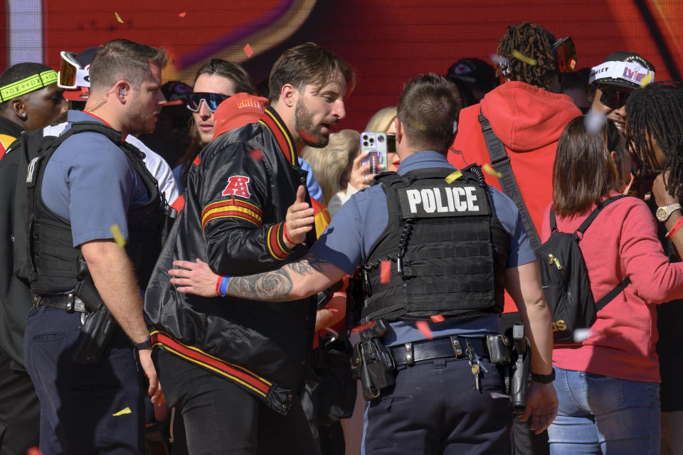 Police escort Kansas City Chiefs tight end Noah Gray and his teammates off the stage after a shooting following their victory parade and rally in Kansas City, Mo., Wednesday, Feb. 14, 2024. Authorities in Kansas City are trying to decipher who was behind the mass shooting that unfolded Wednesday. (AP Photo/Reed Hoffmann)