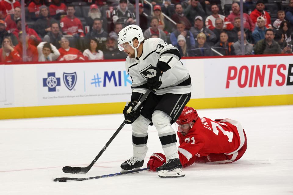 Kings forward Viktor Arvidsson gets the puck knocked off his stick from behind by Red Wings forward Dylan Larkin as he tried to score on a empty net in the third period of the Red Wings' 5-4 overtime loss on Monday, Oct. 17, 2022, at Little Caesars Arena.