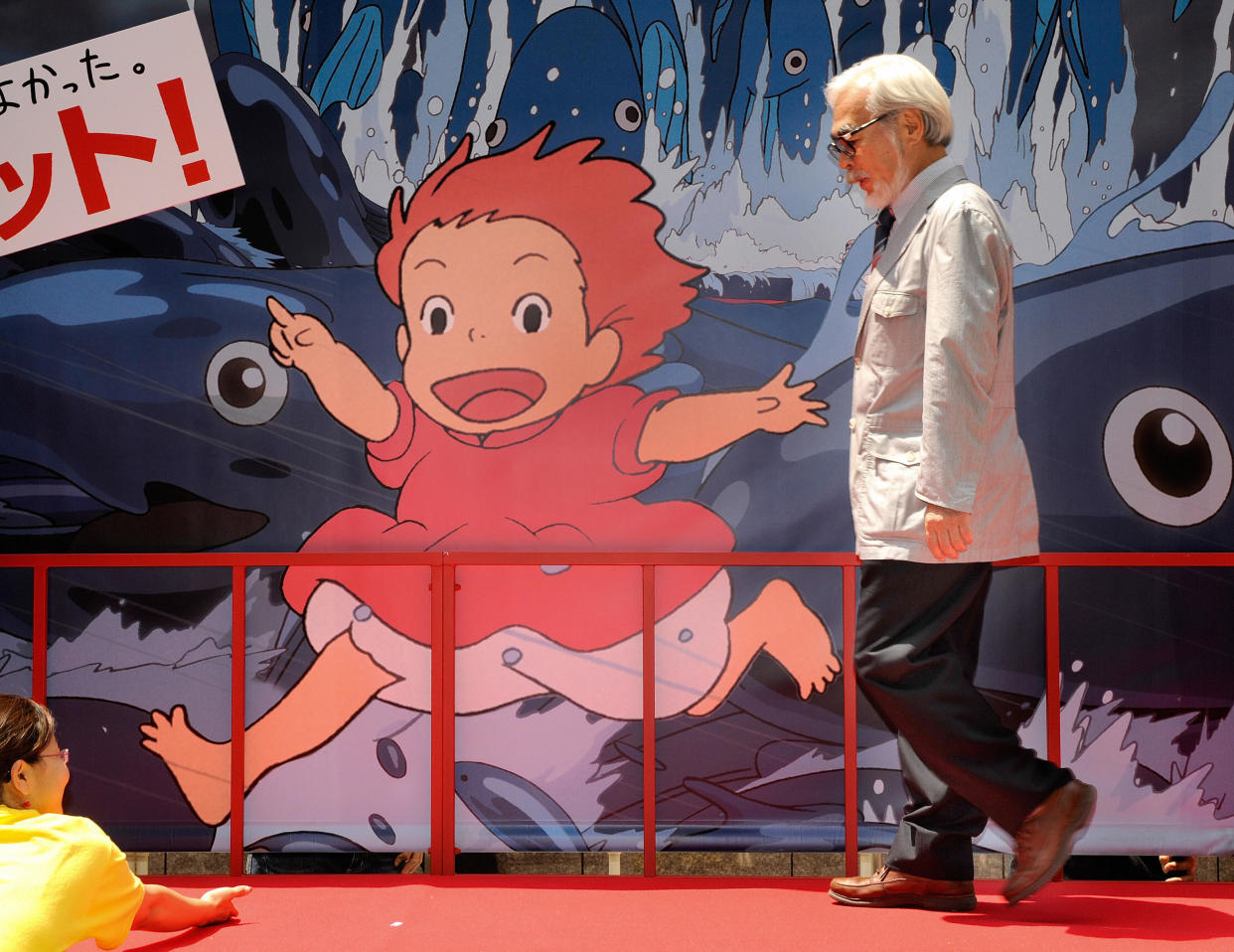 El animador y director de cine japonés ganador del Oscar Hayao Miyazaki pasa junto a un tablero publicitario para una sesión de fotos luego del lanzamiento de su nueva película animada 