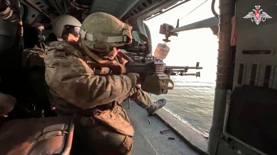 Russian soldiers fire from aboard a Ka-27 helicopter of the Russian Black Sea Fleet during a patrol (Russian Defense Ministry Press Service)