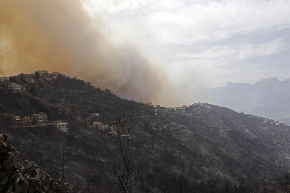 Smoke and fires threaten a village near Tizi Ouzou some 100 km (62 miles) east of Algiers following wildfires in this mountainous region, Tuesday, Aug.10, 2021. Firefighters were battling a rash of fires in northern Algeria that have killed at least six people in the mountainous Kabyle region, the interior minister said Tuesday, accusing "criminal hands" for some of the blazes. (AP Photo/Fateh Guidoum)