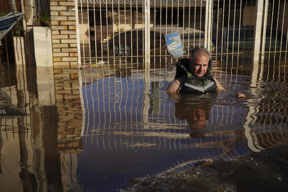 A resident uses a life jacket to cross a flooded street after heavy rain in Canoas, Rio Grande do Sul state, Brazil, Thursday, May 9, 2024. (AP Photo/Carlos Macedo)