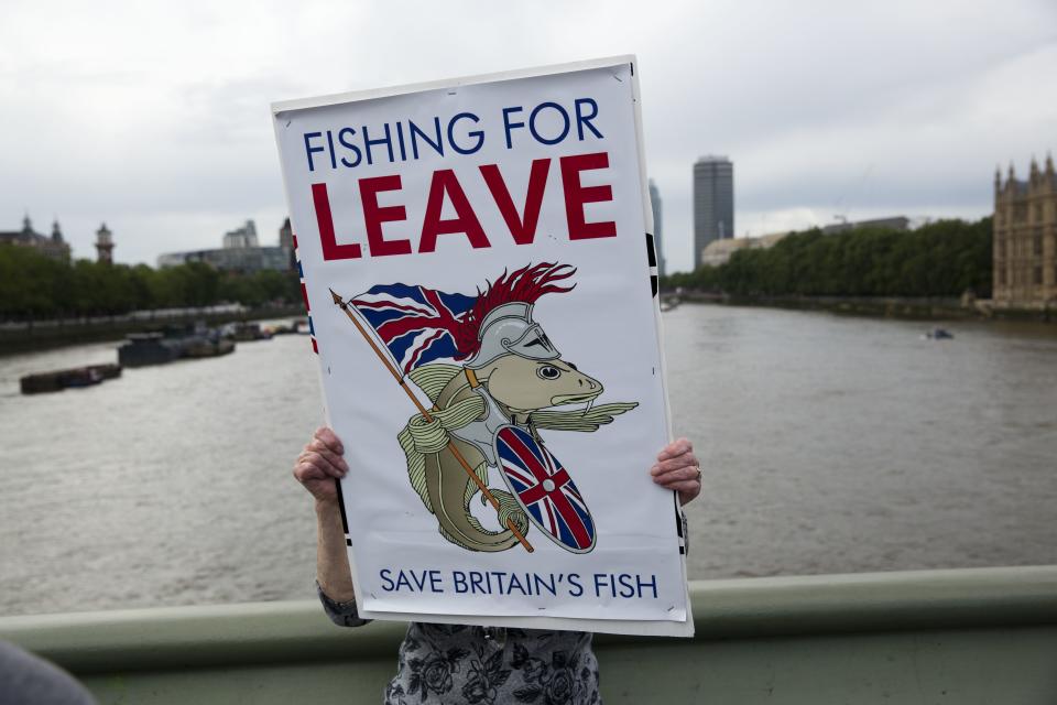 FILE - In this Wednesday, June 15, 2016 file photo, a "Leave" supporter holds a banner on Westminster Bridge during an EU referendum campaign stunt in which a flotilla of boats supporting "Leave" sailed up the River Thames outside the Houses of Parliament in London. Five years ago, Britons voted in a referendum that was meant to bring certainty to the U.K.’s fraught relationship with its European neigbors. Voters’ decision on June 23, 2016 was narrow but clear: By 52 percent to 48 percent, they chose to leave the European Union. It took over four years to actually make the break. The former partners are still bickering, like many divorced couples, over money and trust. (AP Photo/Matt Dunham, File)