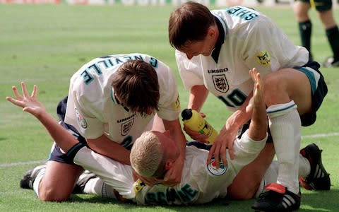 England's Paul Gascoigne lies on his back as he is congratulated by teammates Gary Neville (L) and Teddy Sheringham (R) after scoring the second goal against Scotland - Credit: reuters