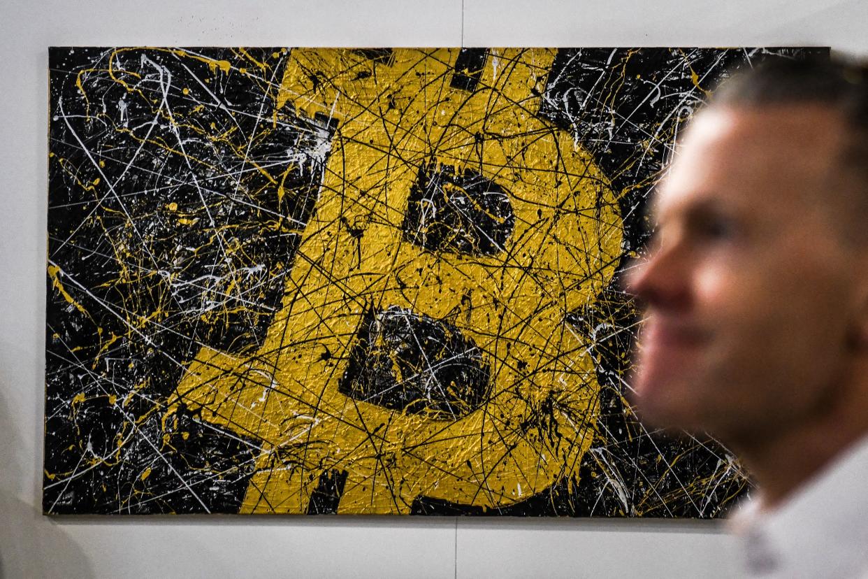 A man walks past artwork depicting the Bitcoin logo during the Bitcoin 2022 Conference at the Miami Beach Convention Center in Miami Beach, Florida, on April 7, 2022. (Photo by CHANDAN KHANNA/AFP via Getty Images)