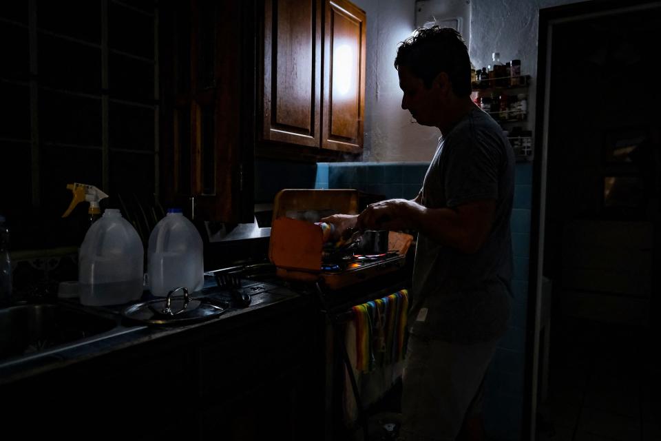 A person cooks in the dark in a home in the Condado community of Santurce in San Juan, Puerto Rico, on Sept. 19, 2022, after the the power went out with the passage of Hurricane Fiona.