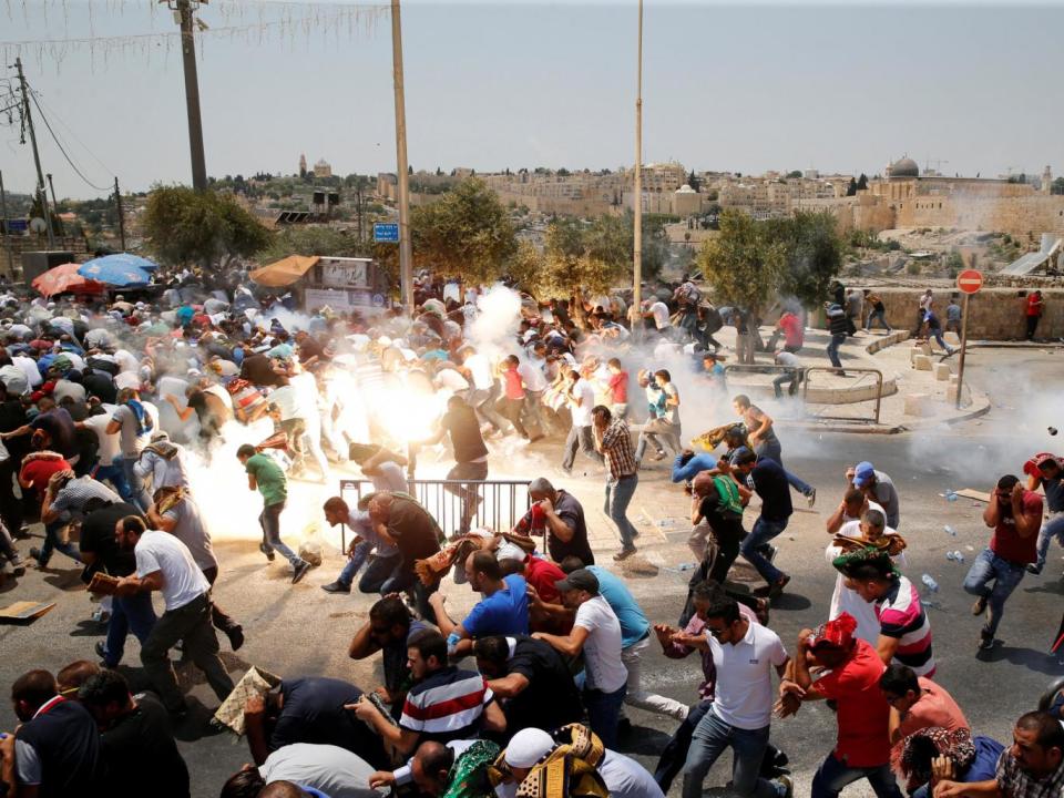 Palestinians react following tear gas that was shot by Israeli forces after Friday prayer on a street outside Jerusalem's Old City (Reuters/Ammar Awad)