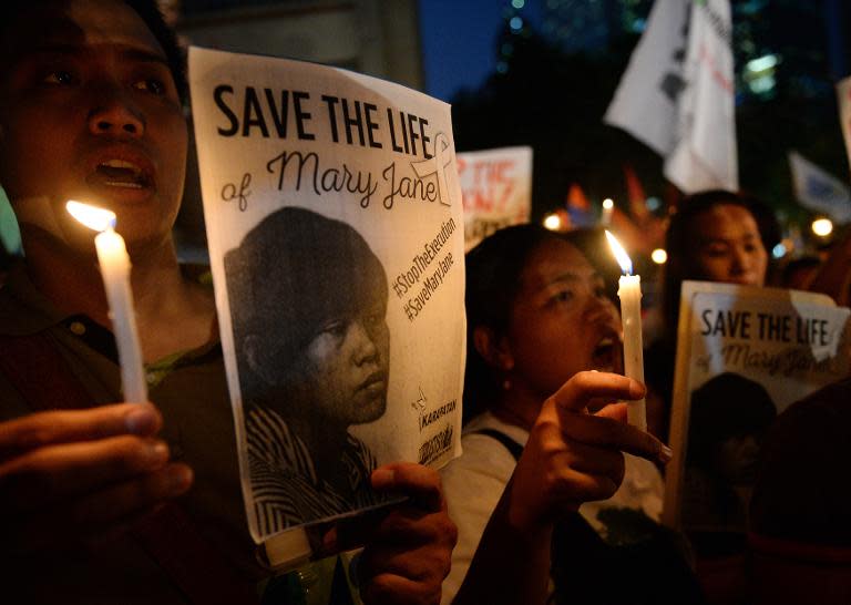 Activists holding candles and portraits of Filipina Mary Jane Veloso shout slogans during a vigil in front of the Indonesian embassy in Manila on April 28, 2015