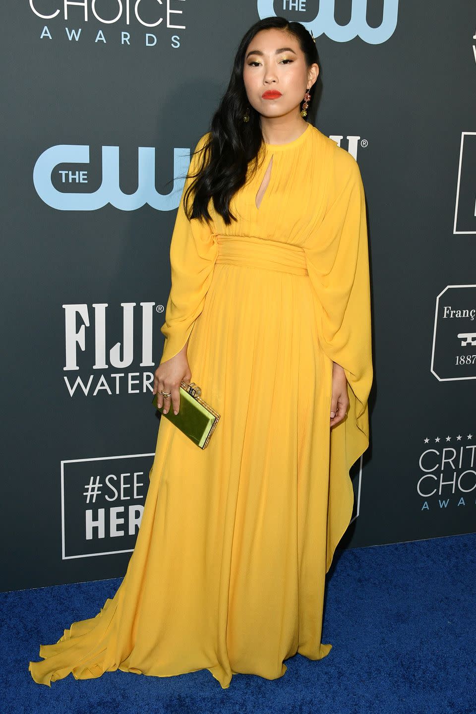 <p>Awkwafina brightens up the blue carpet with this yellow number. She also carries a green clutch.</p>