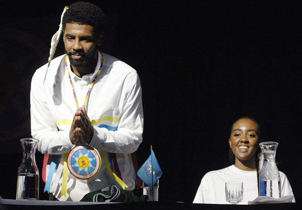 Boston Celtic point guard Kyrie Irving gestures his thanks to a group of students from Little Eagle, S.D. after they gave him a quilt during a naming ceremony in his honor, Thursday, Aug. 23, 2018 at the Prairie Knights Casino north of Fort Yates, N.D. on the Standing Rock Sioux Indian Reservation. Seated next to Irving is his older sister, Asia Irving. Irving's mother, Elizabeth Larson, was an enrolled member of the tribe before being adopted as a youngster. Irving was named Little Mountain by the tribe.(Mike McCleary/The Bismarck Tribune via AP)