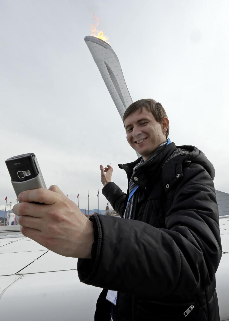 Sartakov Pavel Albertovich takes a selfie in front of the Olympic Cauldron at the 2014 Winter Olympics, Sunday, Feb. 9, 2014, in Sochi, Russia. (AP Photo/Morry Gash)