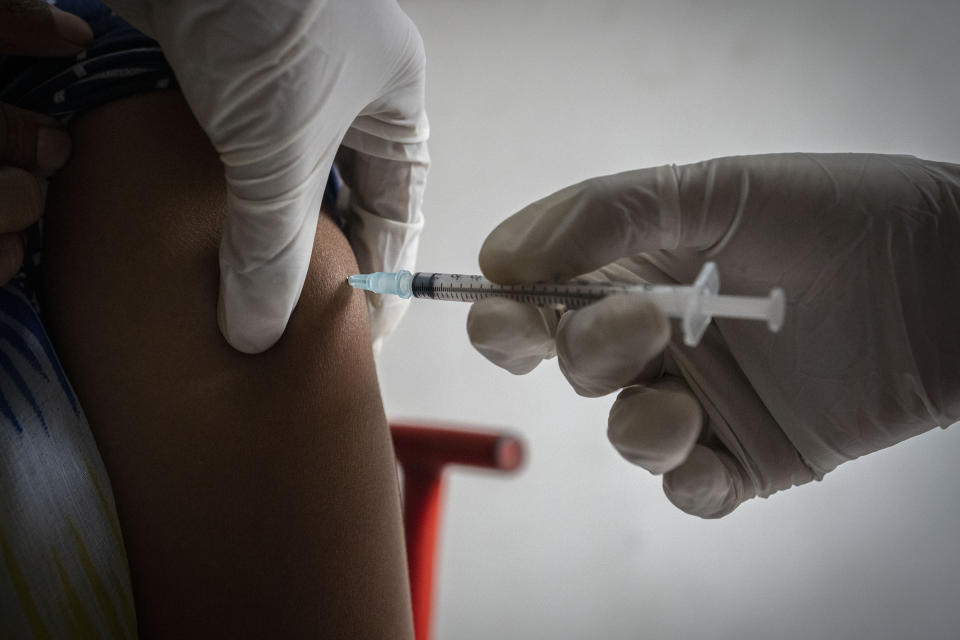 A woman receives her third dose of vaccine for COVID-19 at a private vaccination center in Gauhati, India, Sunday, April 10, 2022. India began offering booster doses of COVID-19 vaccine to all adults on Sunday but limited free shots at government centers to front-line workers and people over age 60. (AP Photo/Anupam Nath)