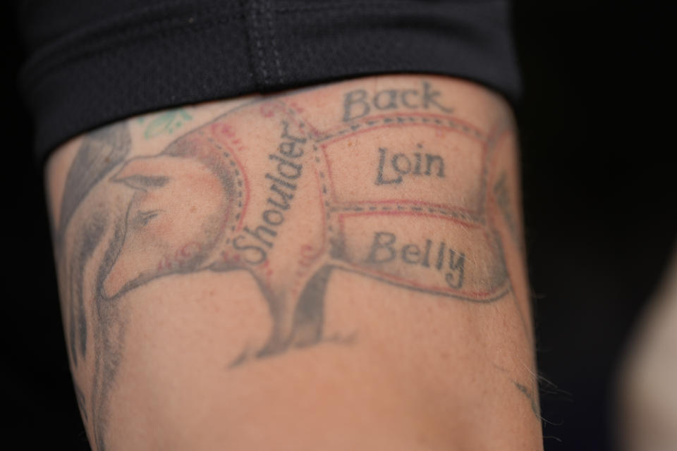 George Logue, pit master for The Shed BBQ and Blues Joint team, shows his pig tattoo at the World Championship Barbecue Cooking Contest, Friday, May 17, 2024, in Memphis, Tenn. (AP Photo/George Walker IV)