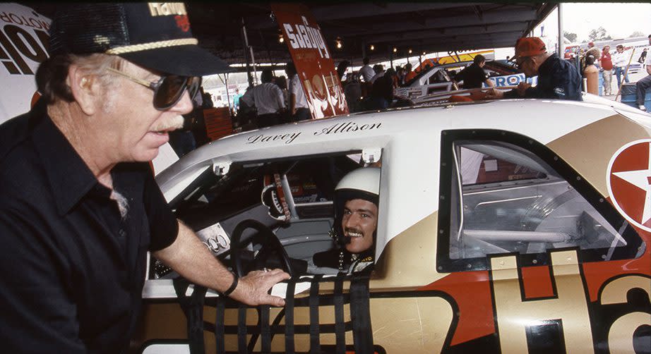 TALLADEGA, AL - JULY 1988: Davey Allison listens to veteran driver Red Farmer in the garage area at the Alabama International Motor Speedway prior to the running of the Talladega DieHard 500 NASCAR Cup race. Farmer was a mentor for the young driver during his career and also served as Allison\