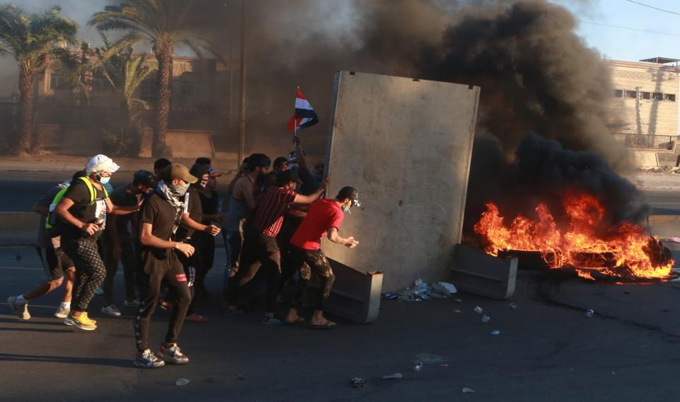 Anti-government protesters set fires and close a street during a demonstration in Baghdad, Iraq, Friday, Oct. 4, 2019. Security forces opened fire directly at hundreds of anti-government demonstrators in central Baghdad, killing some protesters and injuring dozens, hours after Iraq's top Shiite cleric warned both sides to end four days of violence "before it's too late." (AP Photo/Khalid Mohammed)