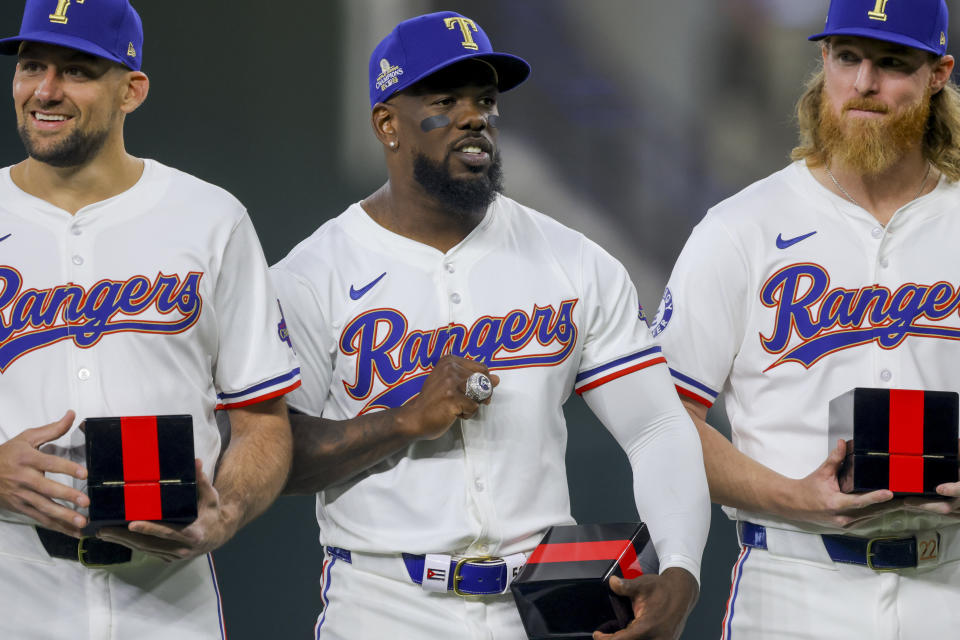 Texas Rangers players Nathan Eovaldi, left; Adolis Garcia, center; and Jon Gray, right, pose with their World Series rings before a baseball game against the Chicago Cubs, Saturday, March 30, 2024, in Arlington, Texas. (AP Photo/Gareth Patterson)
