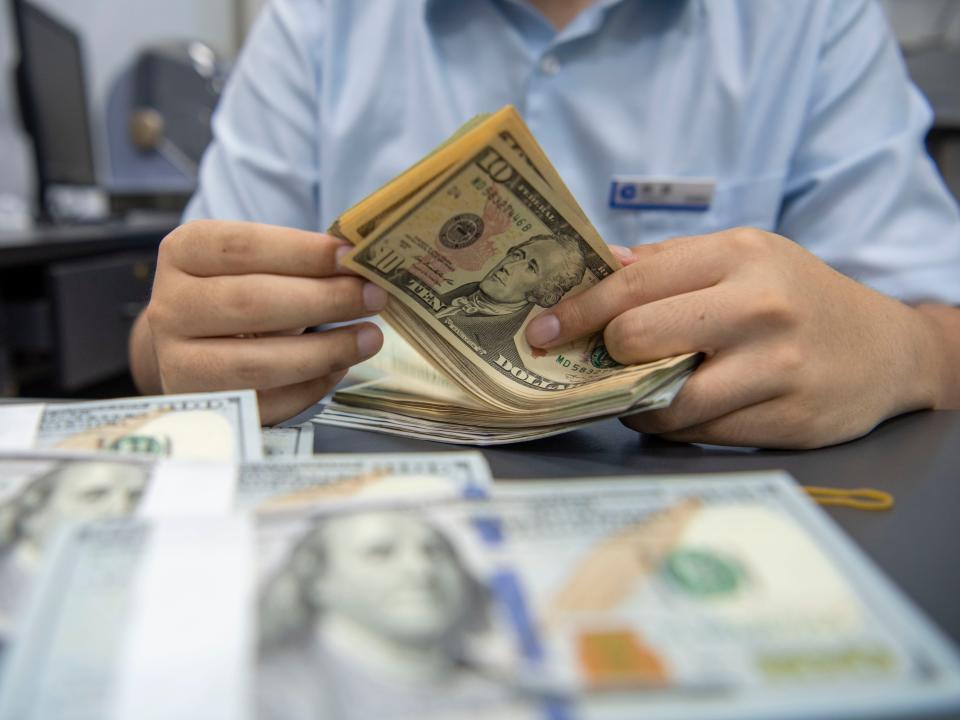 A staff member counts US dollar cash at a bank in Hai 'an, Jiangsu Province, China, Sept 5, 2022.