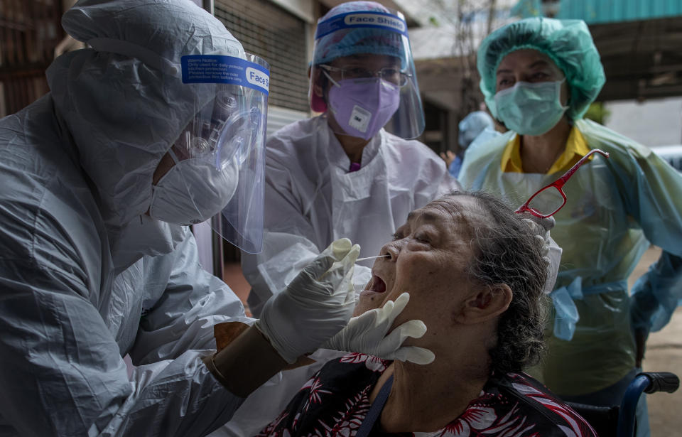 Health workers collect a nasal swab sample from a woman to test for the coronavirus in Bangkok, Thailand, Wednesday, May 6, 2020. Thai health workers started testing community of about 1600 people of Klong Toey slum at a nearby Buddhist temple. (AP Photo/Gemunu Amarasinghe)