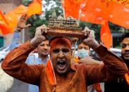 A supporter of ruling Bharatiya Janata Party (BJP) holds a model of proposed Ram Temple in Ayodhya as they celebrate the stone laying ceremony, in New Delhi