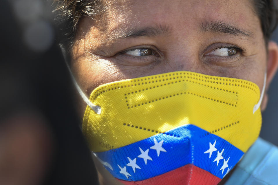 A voter wears a mask against the spread of the new coronavirus, with the design of the Venezuelan flag, as she waits outside a polling station after voting in an election re-run in Barinas, Venezuela, Sunday, Jan. 9, 2022. Voters in the home state of the late Venezuelan President Hugo Chavez are voting again in a special gubernatorial election called after the opposition contender in November's regular contest was retroactively disqualified as he was ahead in the vote count. (AP Photo/Matias Delacroix)