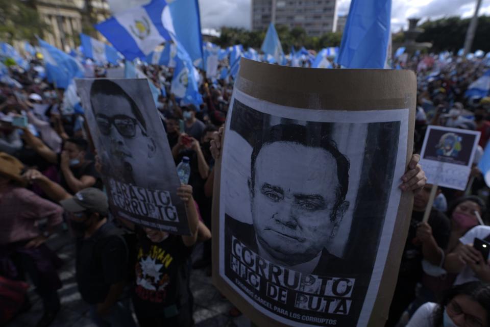 Protesters hold Guatemalan flags and posters alleging corruption fo the president