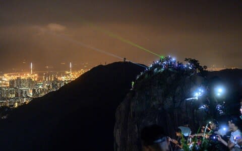 People light up laser beams at the hill top of Lion Rock in Hong Kong  - Credit: AFP
