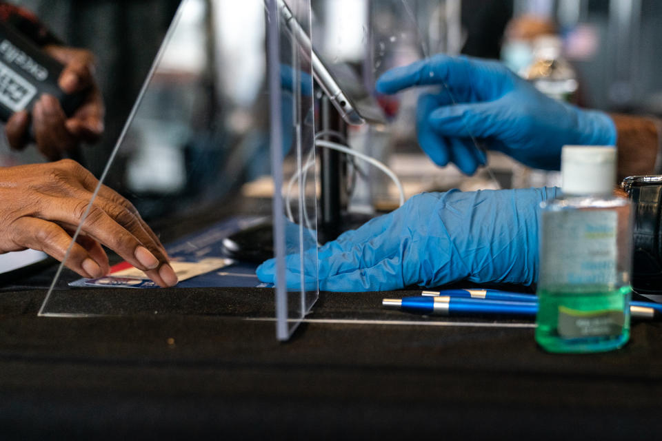 An election official wearing gloves assists a voter at an early voting polling location for the 2020 Presidential election on Monday, Oct. 26, 2020. (Photographer: Jeenah Moon/Bloomberg)