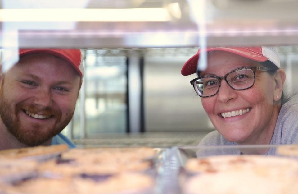 Josh Schmitt and Jenny Lamble look out from a case of pies at the East Side Be Happy Pie Company on Thursday, March 28, 2024.