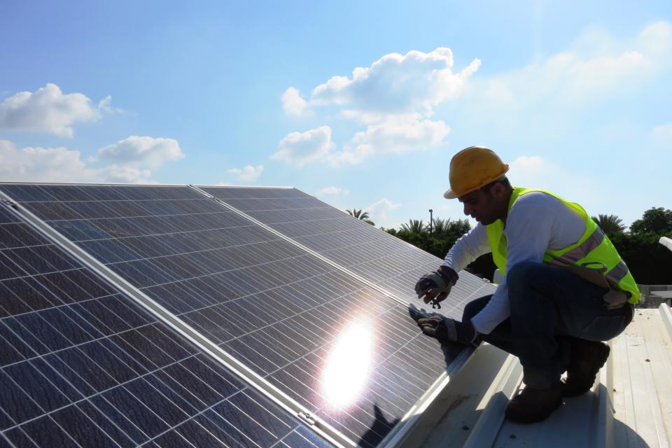 Construction worker installing solar panels on rooftop.