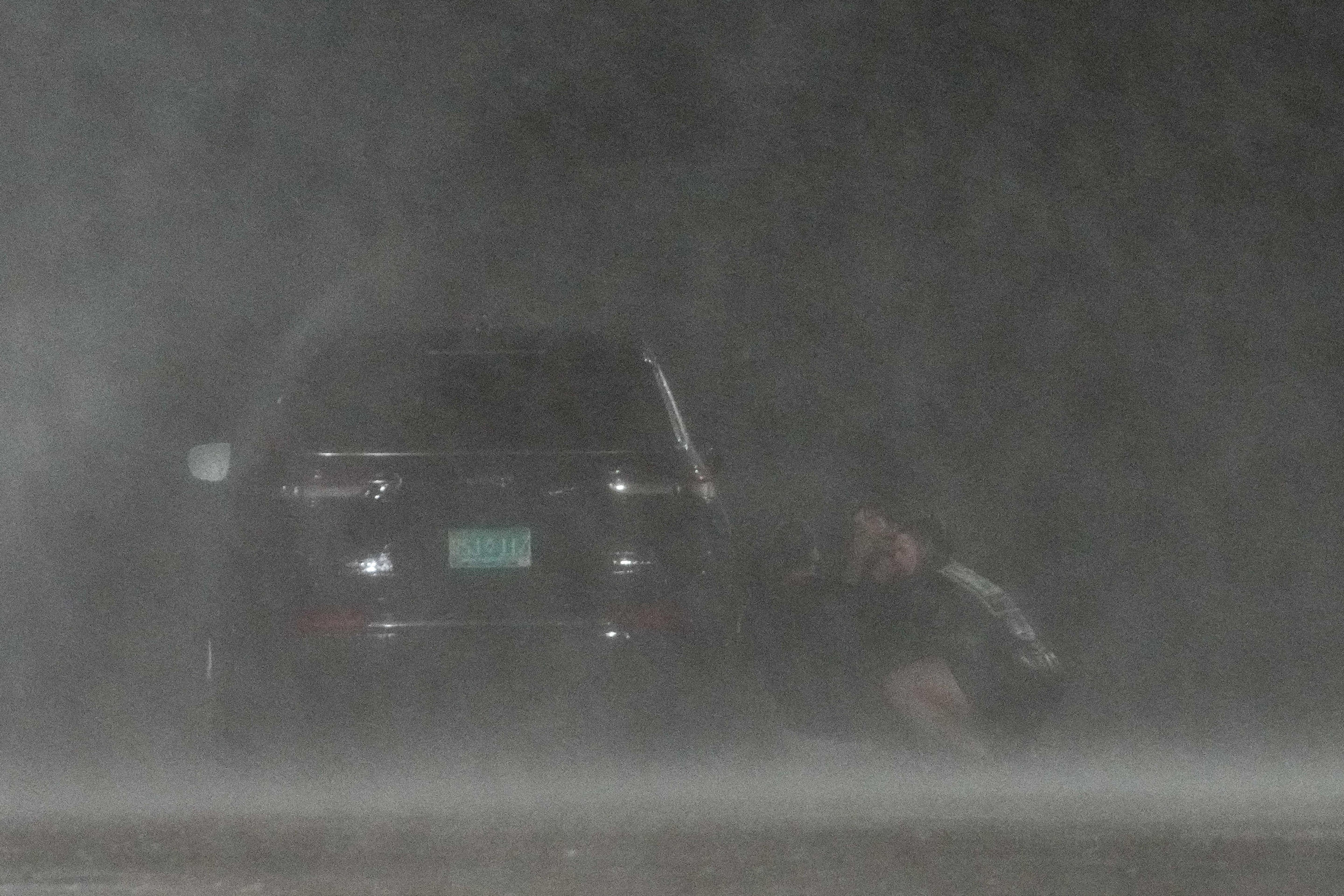 Un grupo de personas se esconde detrás de un automóvil para protegerse del viento y la lluvia del huracán Beryl mientras filman videos para las redes sociales en Bay City, el lunes 8 de julio de 2024.  (John Shapley/Houston Chronicle vía Getty Images)