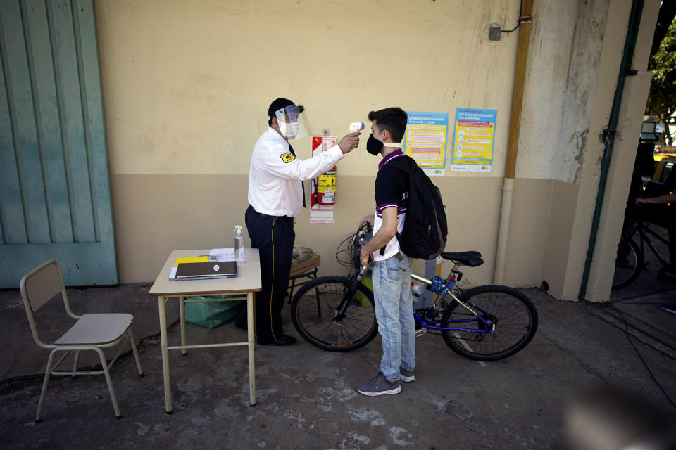 Un guardia de seguridad monitorea la temperatura de un estudiante en la escuela Hipólito Yrigoyen en Buenos Aires, Argentina, el martes 13 de octubre de 2020. (AP Foto/Victor R. Caivano)