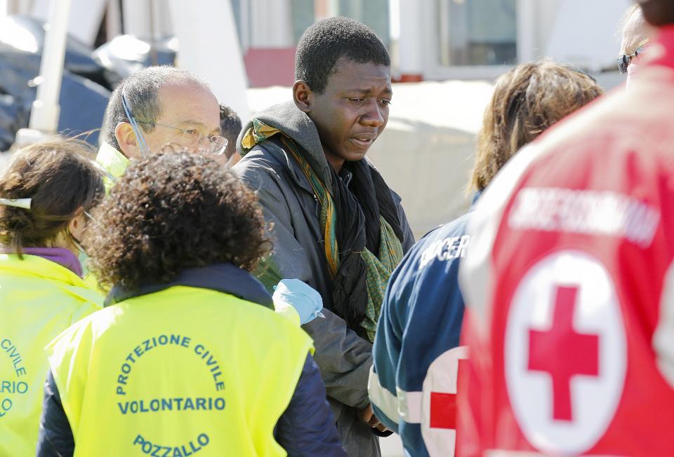 A migrant is helped by Red Cross assistants as he arrives at the Sicilian harbour of Pozzallo