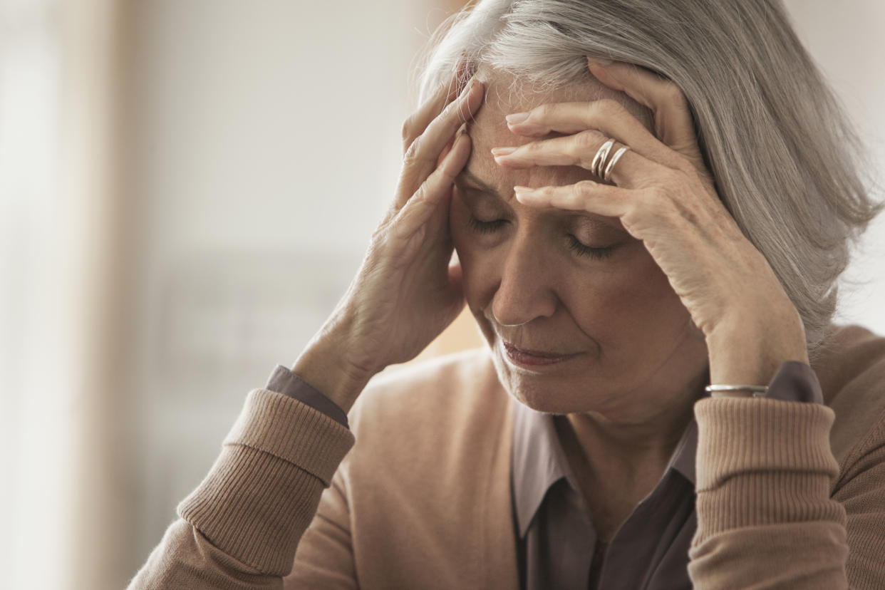 Senior Caucasian woman holding her forehead