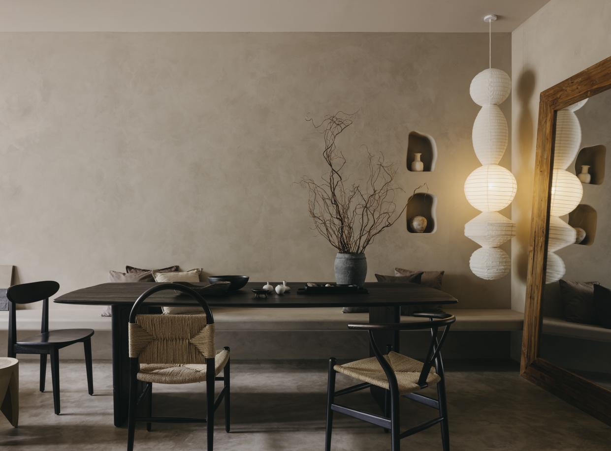  A dining room with an earthy aesthetic and a long, hanging lamp. 