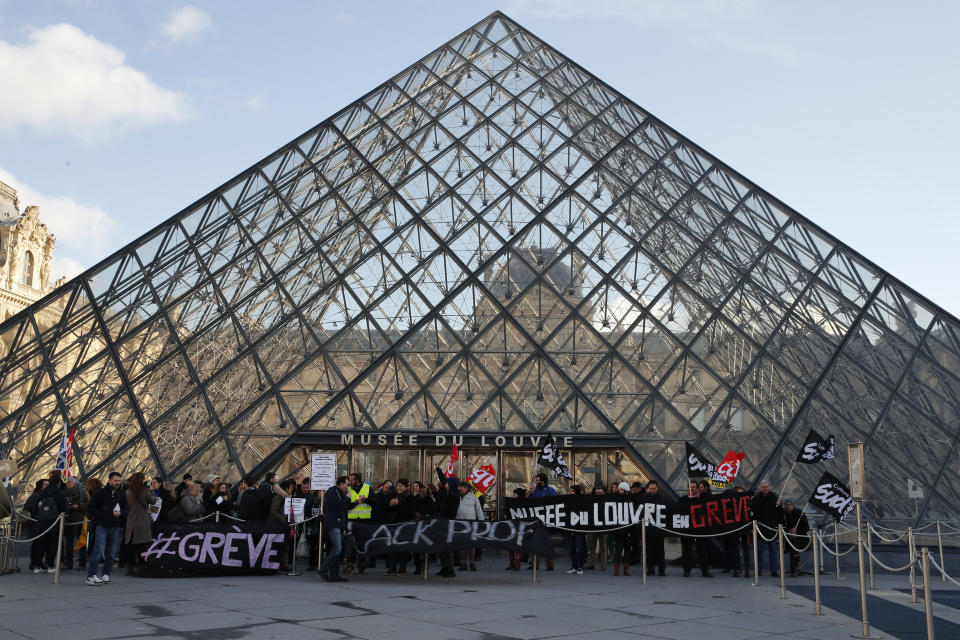 Striking employees hold banners outside the Louvre museum Friday, Jan. 17, 2020 in Paris. Paris' Louvre museum was closed Friday as dozens of protesters blocked the entrance to denounce the French government's plans to overhaul the pension system. (AP Photo/Francois Mori)