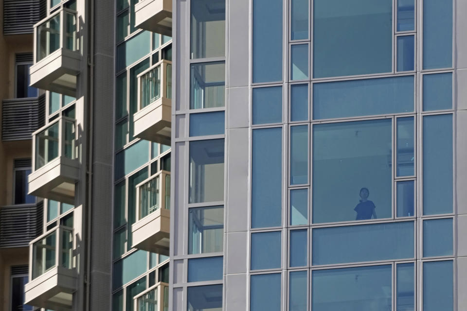 In this Friday, June 11, 2021, photo, a woman stands in a flat of the Grand Central residential building complex where one of a HK$10.8 million (US$1.4 million) 449 square feet single-room flats will be offered as a prize in a coronavirus lucky draw. Coronavirus vaccine incentives offered by Hong Kong companies, including a lucky draw for an apartment, a Tesla car and even gold bars, are helping boost the city’s sluggish inoculation rate. (AP Photo/Kin Cheung)