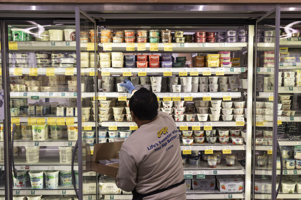 A view of a grocery store worker restocking a refrigerator in Washington, D.C.