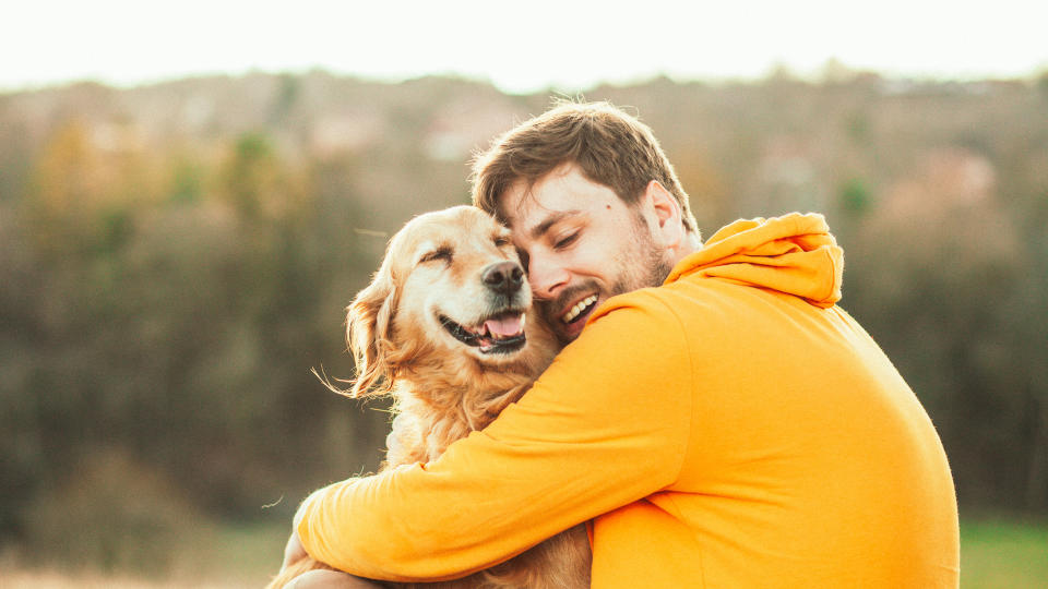 Man cuddling golden retriever